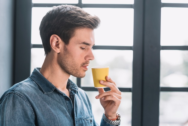 Kostenloses Foto die nahaufnahme eines mannes, der betrachtet, nehmen kaffeetasse in der hand weg