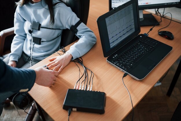 Kostenloses Foto die realität hat grenzen, die vorstellungskraft - nicht. mädchen geht lügendetektor im büro vorbei. fragen stellen. polygraphentest