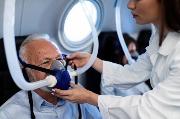 Die Ärztin, die die Sauerstoffmaske eines älteren Patienten in der Druckkammer der Klinik Focus anpasst, ist ein älterer Mann