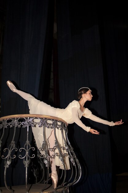 Die schöne Ballerina posiert im langen weißen Kleid