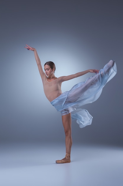 Die schöne Ballerina tanzt mit blauem Schleier auf blauem Hintergrund