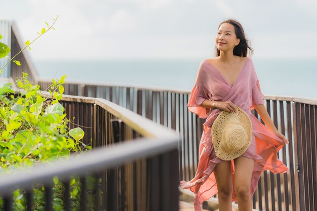 Die schöne junge asiatische Frau des Porträts, die Seestrandozean sucht, entspannen sich in der Urlaubsreise