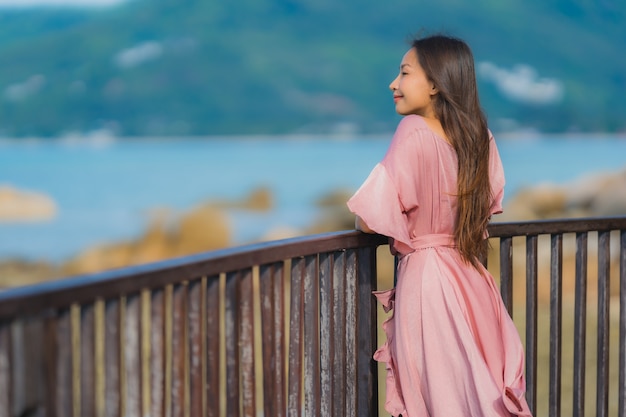 Die schöne junge asiatische Frau des Porträts, die Seestrandozean sucht, entspannen sich in der Urlaubsreise