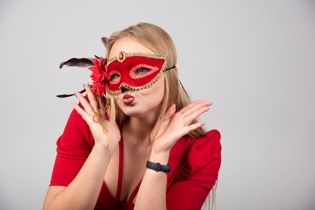Die schöne junge Frau in einer roten mysteriösen venezianischen Maske.