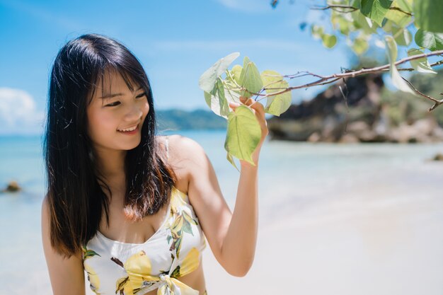 Die schöne junge glückliche Asiatin entspannen sich das Gehen auf Strand nahe Meer.