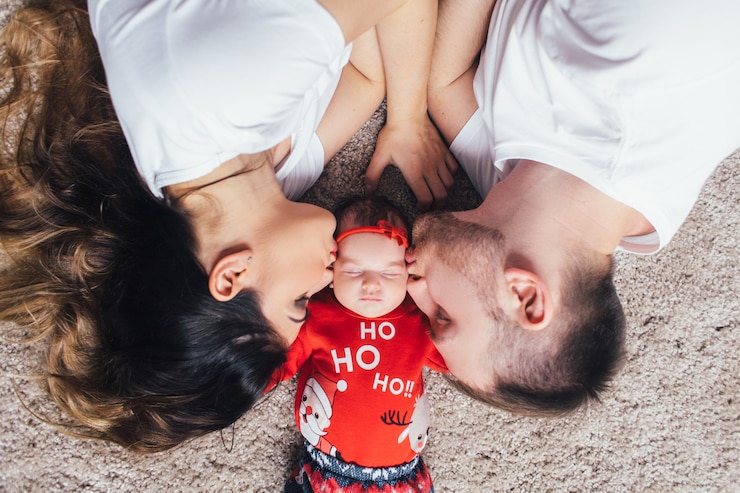 Kostenlose Foto die schönen eltern küssen ihre tochter und liing auf dem boden