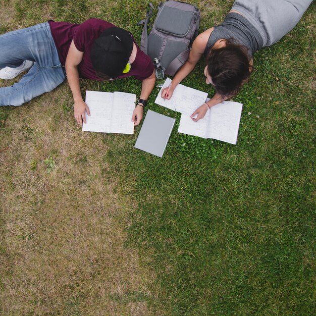 Die Schüler liegen auf dem Gras mit Notebooks