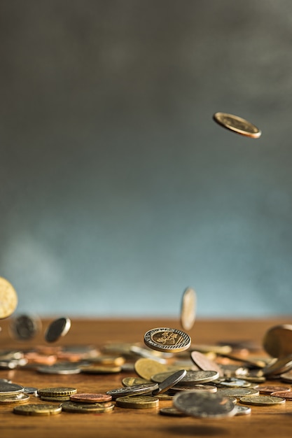 Die Silber- und Goldmünzen und fallenden Münzen auf hölzernem Hintergrund