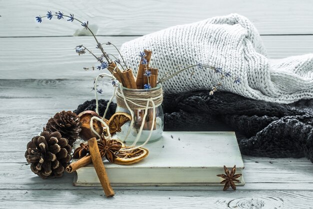 die Tasse Tee auf einem schönen hölzernen Hintergrund mit Winterpullover, altem Buch, Winter, Herbst, Nahaufnahme