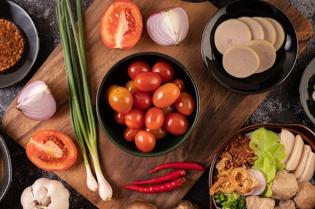 Die Tomaten in der schwarzen Tasse mit Frühlingszwiebeln, Paprika, Tomaten und roten Zwiebeln.