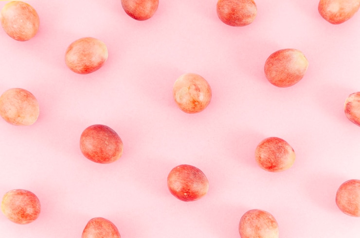 Kostenlose Foto die trauben verteilten sich zufällig über die rosa oberfläche