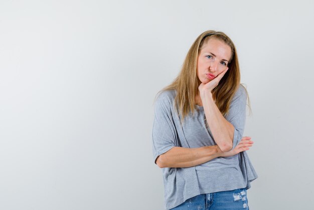 Die traurige Frau denkt, indem sie die Hand auf die Wange auf weißem Hintergrund hält