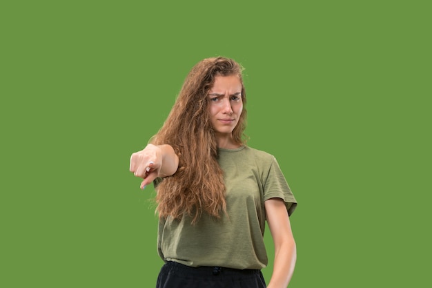 Die überhebliche Geschäftsfrau zeigt Sie und will Sie, halbes Länge Nahaufnahmeporträt auf grünem Hintergrund.