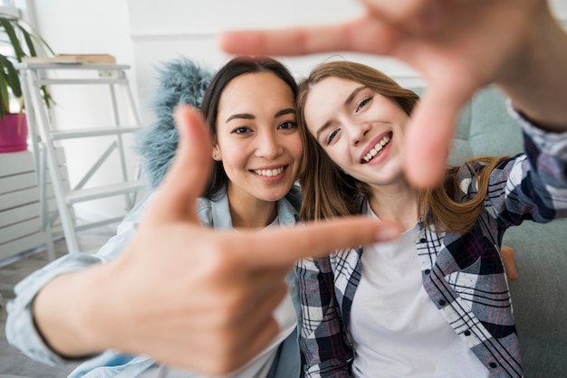 Kostenloses Foto die umfassung der mädchen, die fotorahmen mit den händen lächeln und machen, mögen selfie