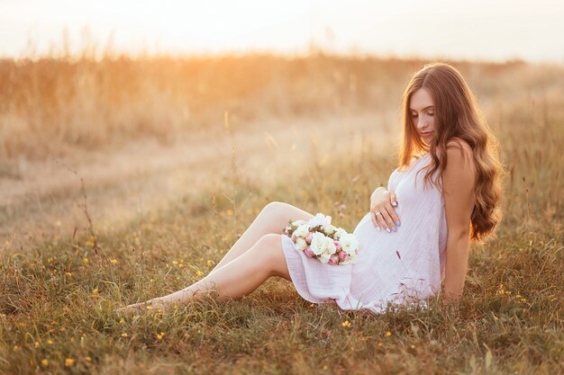 Die zukünftige Mutter, die auf dem Gras sitzt
