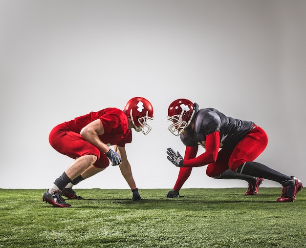 Die zwei American-Football-Spieler in Aktion auf grünem Gras und grauem Hintergrund.