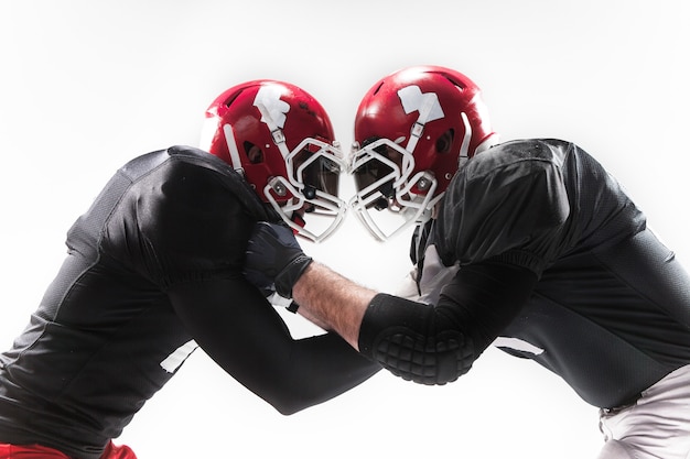 Die zwei Fitnessmänner als American-Football-Spieler kämpfen auf weißem Hintergrund