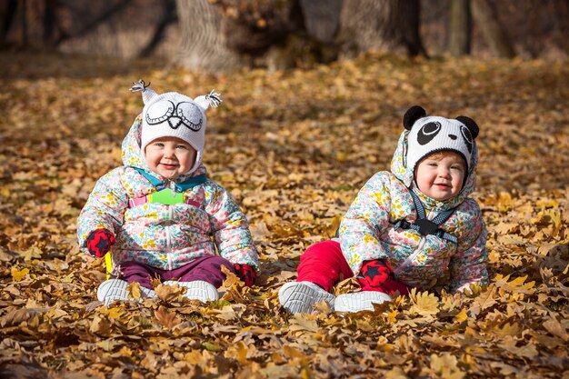 Die zwei kleinen Mädchen sitzen im Herbstlaub