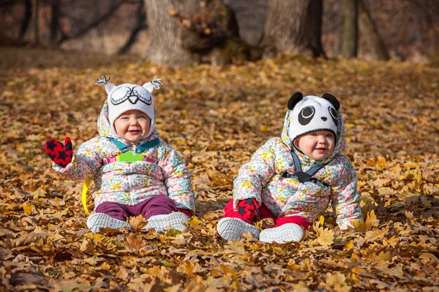 Die zwei kleinen Mädchen sitzen im Herbstlaub