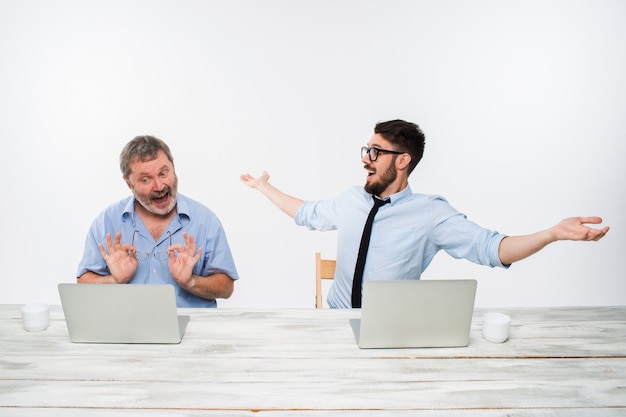 Die zwei Kollegen arbeiten zusammen im Büro auf weißem Hintergrund. beide schauen auf die Computerbildschirme. Beide überrascht. Konzept der positiven Emotionen und guten Nachrichten