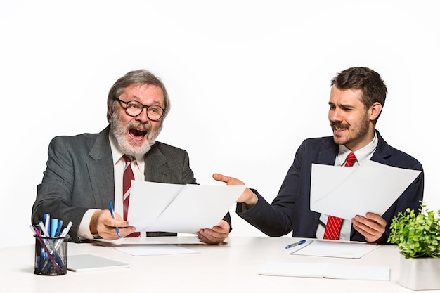 Die zwei Kollegen arbeiten zusammen im Büro auf weißem Hintergrund. Sie diskutieren aktiv und emotional aktuelle Pläne