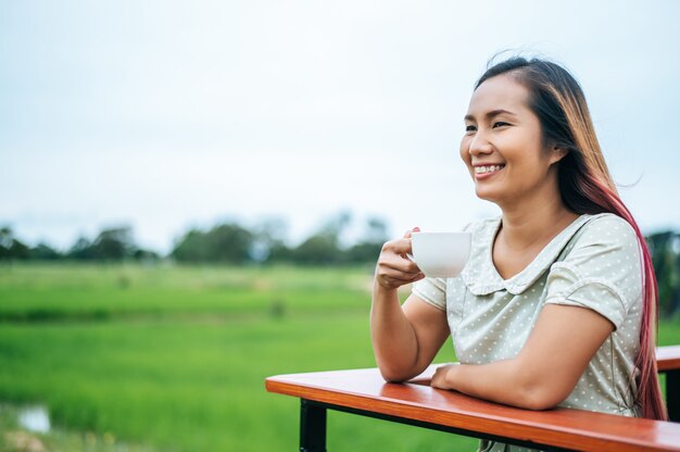 Diese Frau stand glücklich auf der Wiese und trank Kaffee.