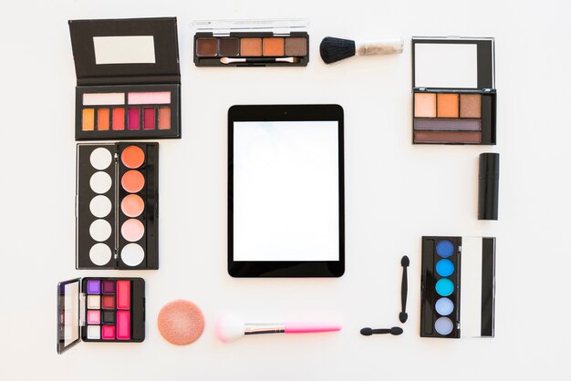 Digitale Tablette des leeren Bildschirms mit Schönheitsprodukten für Berufsmake-up über weißem Hintergrund