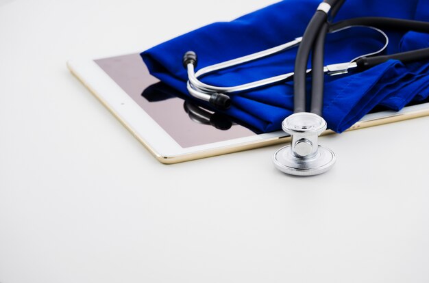 Digitale Tablette; Stethoskop und medizinisches Kleid auf weißem Hintergrund