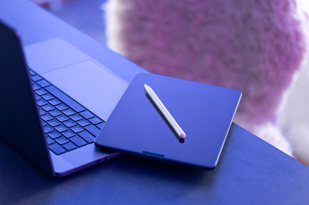 Digitaler Tablet-Stilus-Stift und Laptop auf dem Desktop in naher Nähe