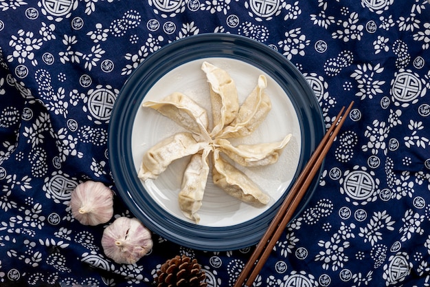 Dim Sum in einer weißen Platte mit Knoblauch auf einem blauen mit Blumenhintergrund