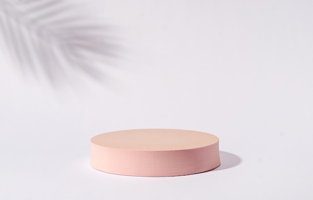 Disc-zylinder-mock-up-plattform-sockelständer rosa für werbeprodukte auf grauem hintergrund und schattenpalme und kopienraum. minimales trendkonzept.