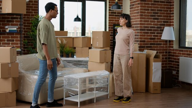Diverse Paare ziehen zusammen und packen Möbel im neuen Zuhause aus und freuen sich über die Investition in den Umzug. Neuanfänge in einer auf Hypothek und Darlehen gekauften Eigentumswohnung.
