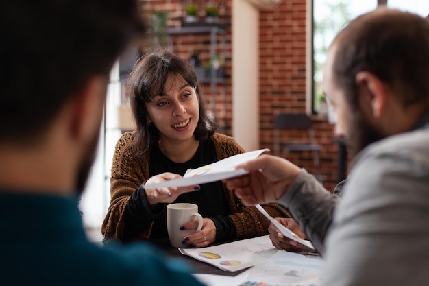 Kostenloses Foto diverse teams, die papiere mit marketingstatistiken teilen, die an der geschäftlichen zusammenarbeit bei der planung des unternehmensumsatzes arbeiten. multiethnische geschäftsleute, die an projekt-brainstorming-ideen im startup-büro arbeiten