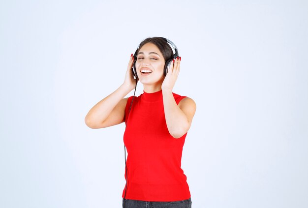 DJ-Mädchen im roten Hemd, das Kopfhörer trägt und eine gute Musik hört.