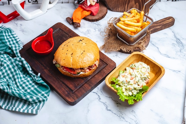 Döner im Brot mit Ketchup auf einem Brett mit Pommes Frites und einem Hauptsalat