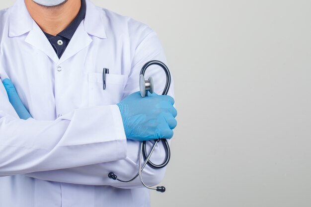 Doktor, der Arme kreuzt, während er Stethoskop im weißen Kittel hält
