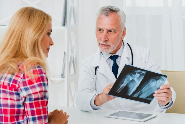 Doktor, der dem Patienten Röntgenstrahl zeigt