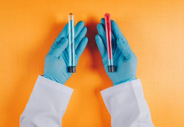 Kostenloses Foto doktor, der laborfläschchen in beiden händen auf orange hält