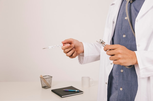 Doktor die Hände mit einem Thermometer und Stethoskop