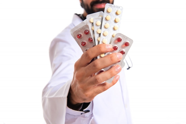 Doktor hält Pillen über weißem Hintergrund