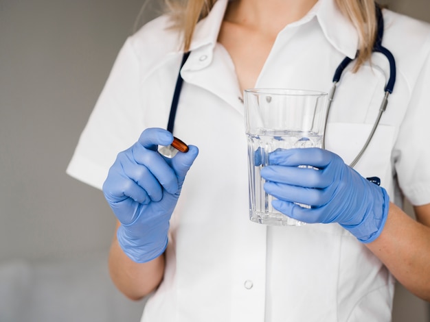 Doktor hält Wasserglas und Pille