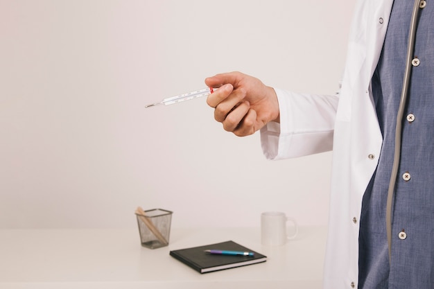 Doktor Hand mit themometer im Büro