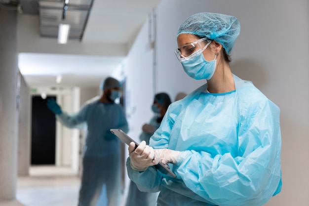 Kostenloses Foto doktor in der schutzkleidung, die eine tablette betrachtet