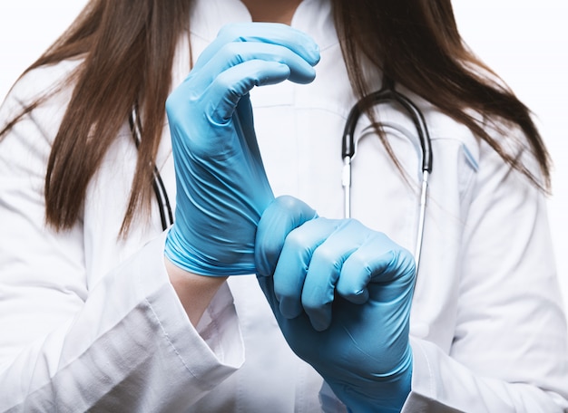 Doktor in einem weißen Kittel mit Stethoskop, Handschuhe tragend.