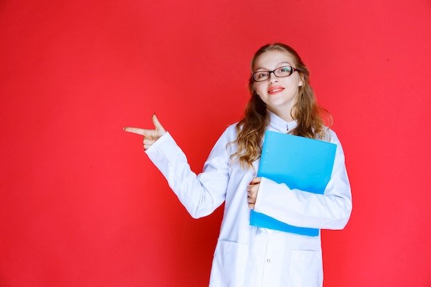 Doktor mit einem blauen Ordner, der nach links zeigt.