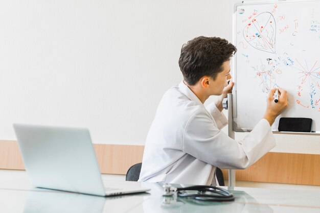 Doktor mit Laptopschreiben auf whiteboard