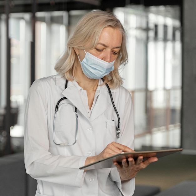 Doktor mit medizinischer Maske, der ihre Notizen überprüft