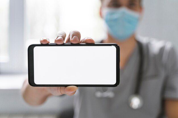 Doktor mit medizinischer Maske, die Smartphone hält