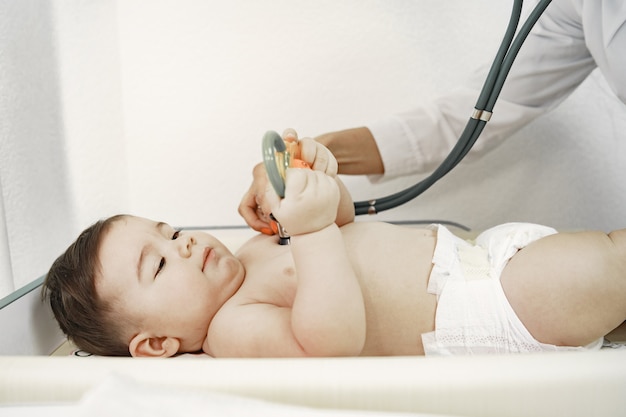 Doktor mit Stethoskop. Baby ohne Kleidung. Untersuchung durch einen Arzt.