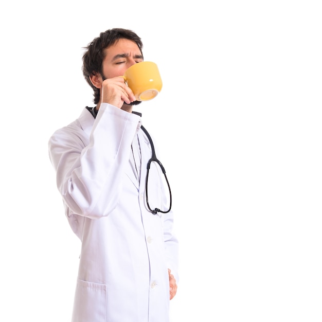 Doktor trinkt Kaffee auf weißem Hintergrund